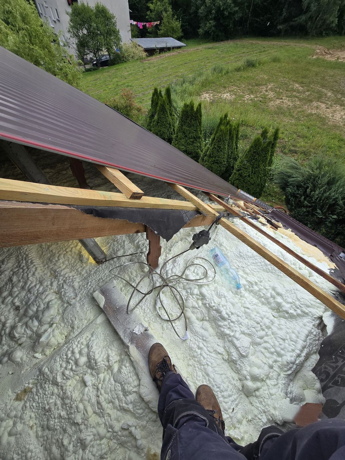 Dłoń aplikatora sprawdza utwardzoną pianę PUR na połaci dachu